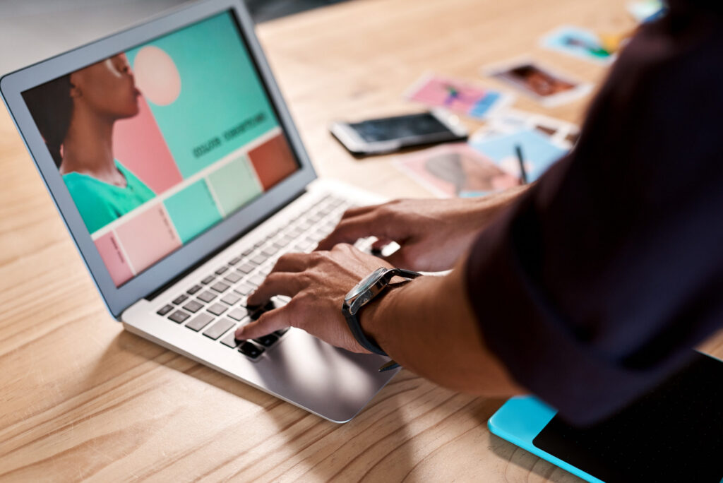 A professional refining color palettes and visuals on a laptop to ensure brand consistency across creative assets.